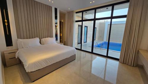 a bedroom with a large bed and a large window at Al Mona Resort 2 شاليه المنى in Al Khobar