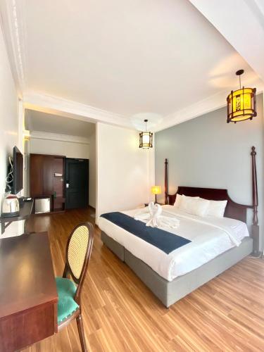 Khách Sạn Thủ Đô Formerly Impressive Hotel في هانوي: غرفة نوم بها سرير كبير وطاولة