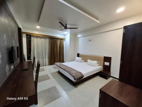 a bedroom with a bed and a desk and a television at Hotel Pride Executive in Satara
