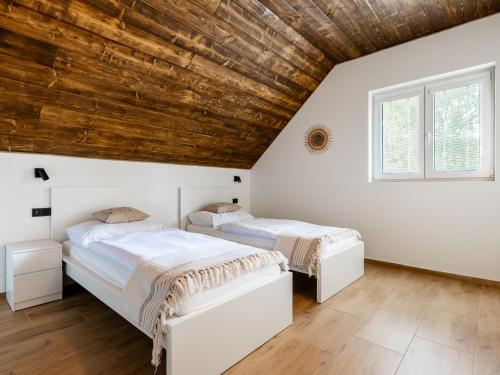 two beds in a bedroom with a wooden ceiling at Apartmány Bližší Lhota in Bližší Lhota