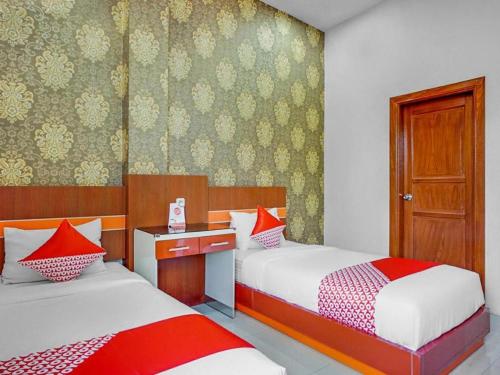 Un dormitorio con dos camas con almohadas rojas y blancas. en OYO 3157 Grand City Inn, en Pampang