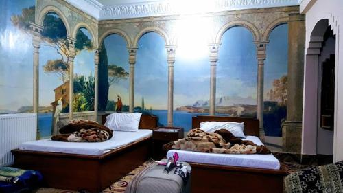 two beds in a room with a painting on the wall at Hotel Qasr-e-Naz in Dargai