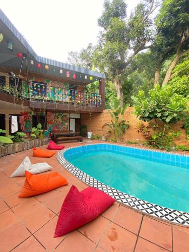 a pool with red and orange pillows in front of a house at Chillin' House in Cat Ba