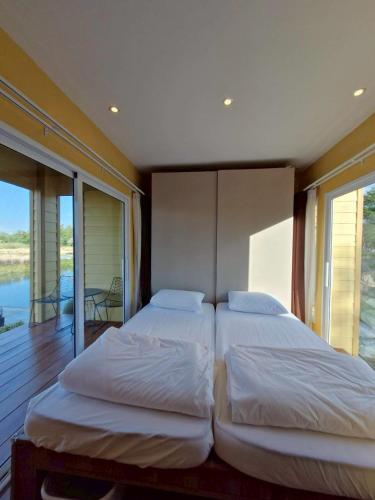 two beds in a bedroom with a balcony at ห่มฟ้าโพธิ์แค้มป์ปิ้ง in Ban Wang Sak