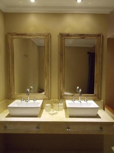 two sinks in a bathroom with two mirrors at Noha Casa de Campo in Colón