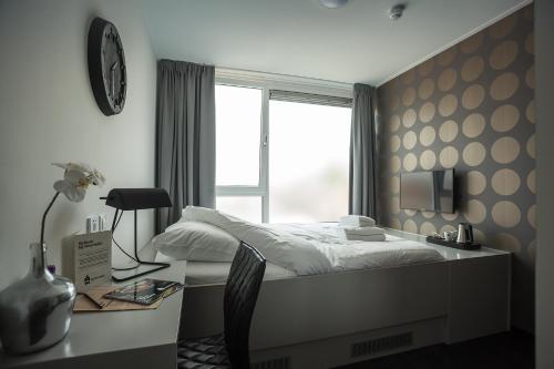 a bedroom with a bed and a desk and a window at Stravinsky Slapen in Hengelo