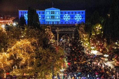 a crowd of people in front of a blue building with christmas lights at Plaka Hideaway Suite in Athens