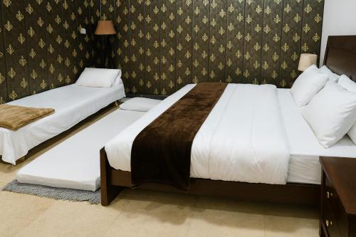 een hotelkamer met 2 bedden en een muur bij Pinewood Guest House in Islamabad