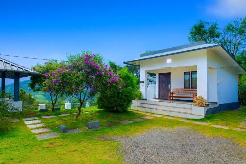a small white house with a bench in a yard at Vythiri Silver Mist Hilltop Villa By VOYE HOMES in Vythiri