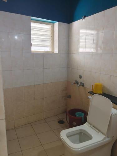 a bathroom with a toilet and a window at Vinayaka Deluxe Lodge in Kushālnagar