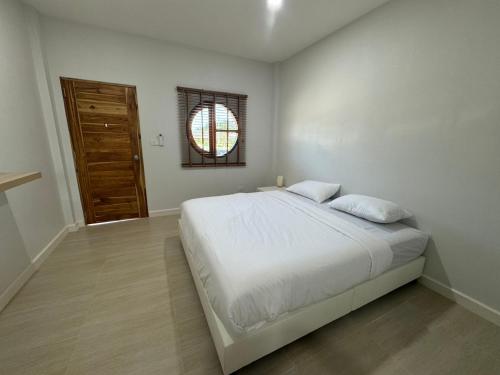 una camera da letto bianca con un letto e una finestra di The9motel a Ngao