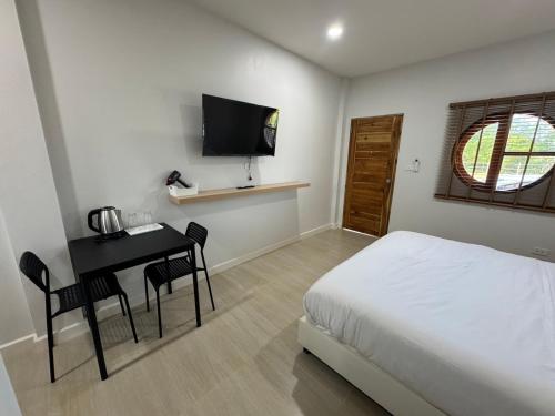 una camera da letto con un letto, una scrivania e una televisione di The9motel a Ngao