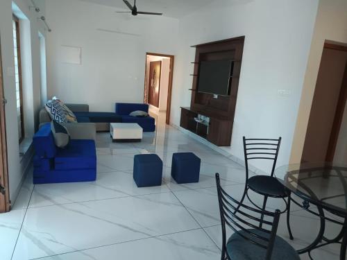 een woonkamer met een blauwe bank en stoelen bij Aathira Agri Homes in Trichūr