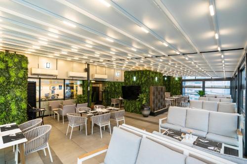 a restaurant with white chairs and tables and plants at Samaya Hotel Deira in Dubai