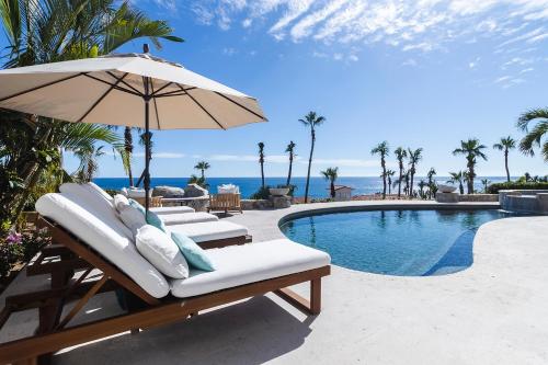 a pool with lounge chairs and an umbrella next to a swimming pool at Casa Sirena in San José del Cabo