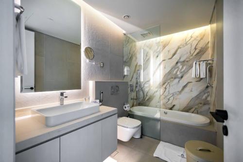 a bathroom with a sink and a tub and a toilet at Casa Royale Vacation Home - Dubai Marina in Dubai