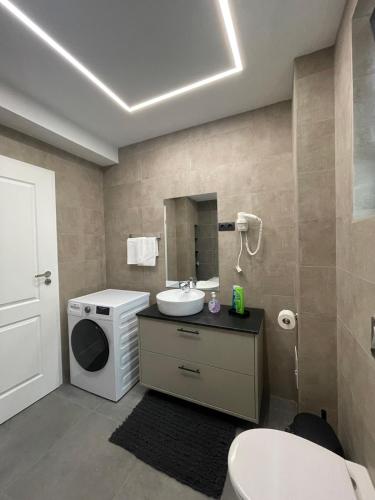 a bathroom with a sink and a washing machine at Noah Apartment Self Check-in Otopeni in Otopeni