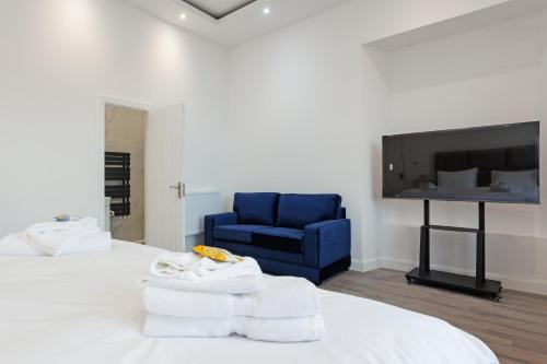 a bedroom with a blue chair and a bed with towels at Savoy 5 in Ayr