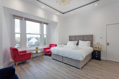 a bedroom with a large bed and two red chairs at Savoy 5 in Ayr