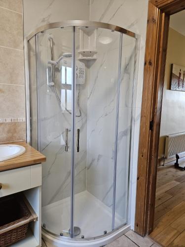 a glass shower in a bathroom with a sink at Rosswood House in Donegal