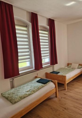 two beds in a room with red curtains at Ferienwohnung Lamm in Göppingen