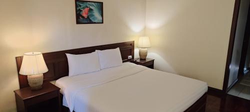 a bedroom with a white bed and two lamps at Puangpen Villa Hotel in Hua Hin
