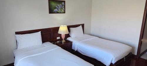two beds in a room with a lamp on a table at Puangpen Villa Hotel in Hua Hin
