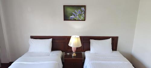 2 letti in una camera d'albergo con una lampada tra loro di Puangpen Villa Hotel a Hua Hin