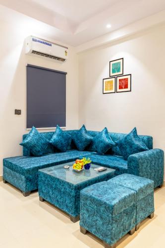 ein Wohnzimmer mit blauen Sofas und einem Bildschirm in der Unterkunft Noida business suites 141 in Noida