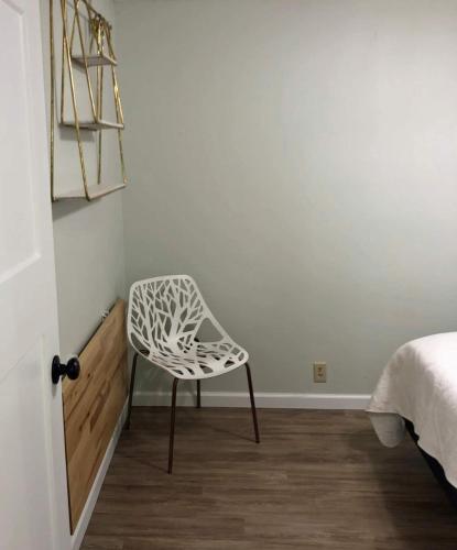 a white chair sitting in a room next to a bed at Quiet-Clean-Cottage-Dogs Kitchen in Tallahassee