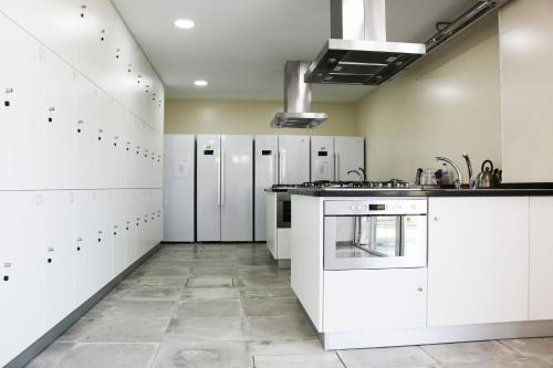 a large white kitchen with white cabinets and appliances at HI Viseu - Pousada de Juventude in Viseu