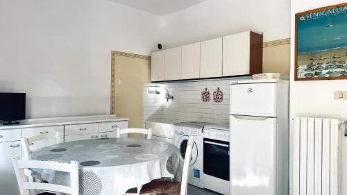 een keuken met een tafel en een witte koelkast bij Bilocale fronte mare - RM08 in Senigallia