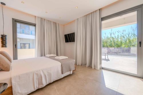 een slaapkamer met een bed en een groot raam bij Alati Suites - Stegna Beach in Vrachonisída touArchangélou