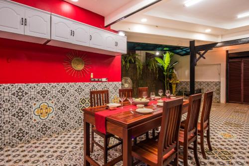 SATTA Private Pool Grill & Chill Villa في سيام ريب: غرفة طعام مع طاولة وجدار احمر