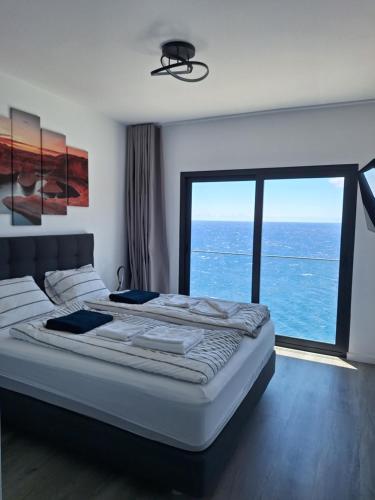 a bedroom with a large bed with a large window at Cliff Residence Ocean View in Gaula