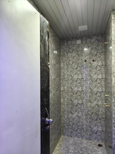 a bathroom with a shower with a stone wall at Hotel Sky Grand in Guwahati