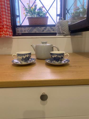 twee theekopjes en een theepot op een aanrecht bij Laura's Cottage in Calatabiano
