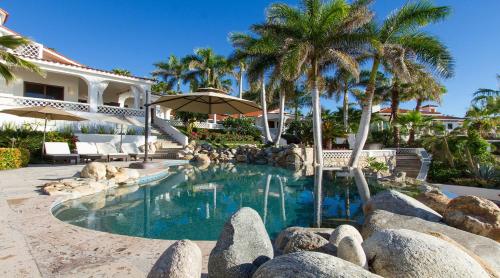 a swimming pool in front of a house with palm trees at Casa Edwards in San José del Cabo