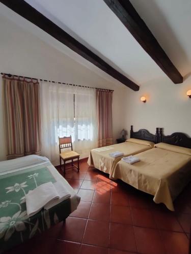 a bedroom with two beds and a chair and a window at Casa Rural Ivanrey in Ivanrey