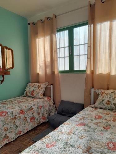 two beds in a room with two windows at Recanto aconchegante próximo ao mar in Vila Velha