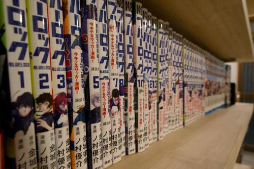 a row of comic books on a wall at 漫画のある家 in Yamatokoriyama