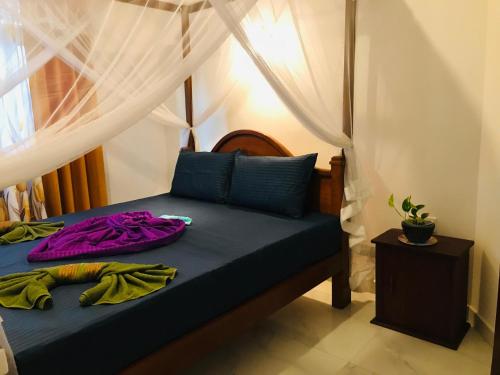a bedroom with a bed with purple clothes on it at Dream Villa in Batigama