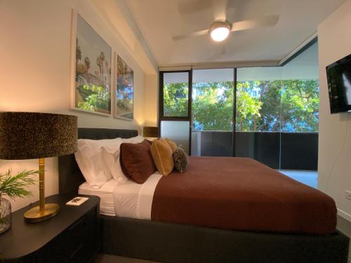 a bedroom with a bed and a lamp and windows at Urban Retreat Homestay - Shared Apartment with Queen Bed and Private Ensuite in Brisbane