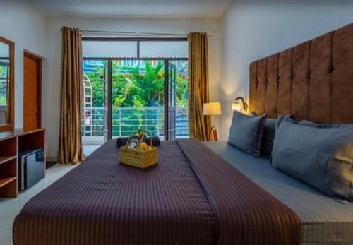 a bedroom with a large bed with a large window at Hotel Sky Blue Baga Goa in Baga