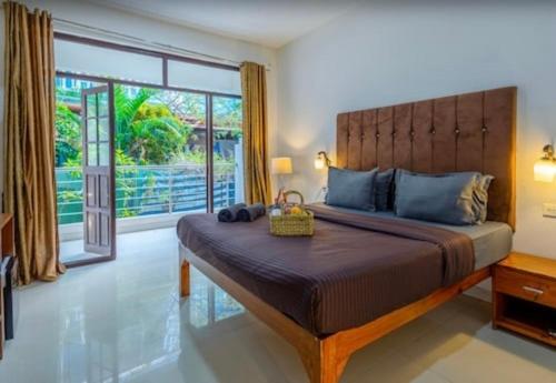 a bedroom with a large bed with a large window at Hotel Sky Blue Baga Goa in Baga