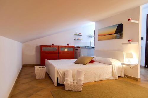 a bedroom with a white bed and a kitchen at Boa Vista San Vito - Area Fitness, Barbecue Area, Tennis Court in San Vito lo Capo