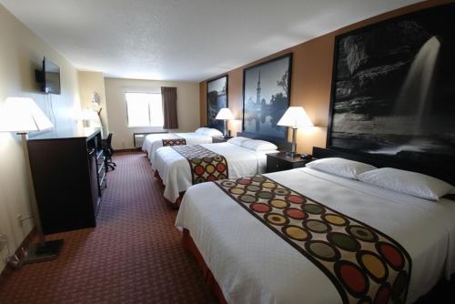 a hotel room with three beds and a television at Coratel Inn and Suites By Jasper Wichita North in Wichita