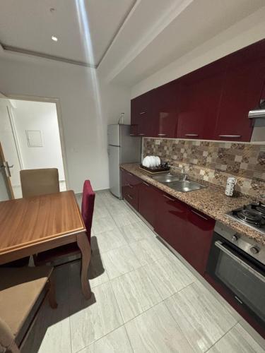 a kitchen with red cabinets and a wooden table at Résidence Maha in Hammam Sousse