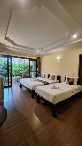 three beds in a room with a large window at ปราณบุรีน้อยรีสอร์ท in Ban Nong Sua