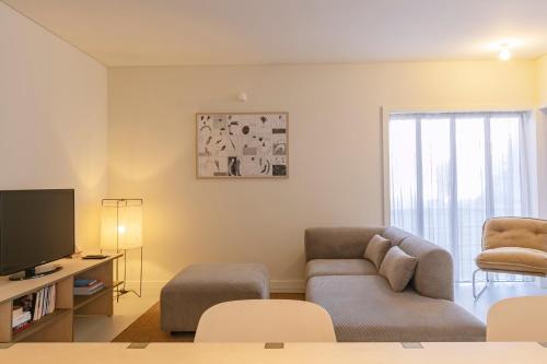 a living room with a couch and a tv at Apartamento Sacadura Cabral - a 2 min da praia in Vila do Conde